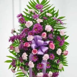 Standing floral spray with purple and pink flowers and a lavender ribbon
