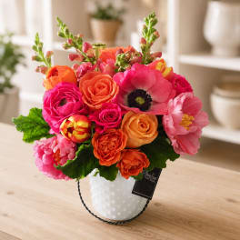 Bright mixed bouquet in a white textured vase on a table