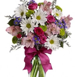 Bouquet of pink roses, white daisies, and purple flowers in a glass vase