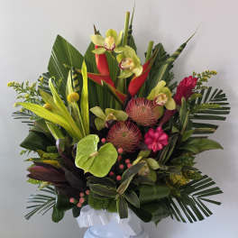 Tropical flower arrangement in a white pedestal vase with pink and green blooms