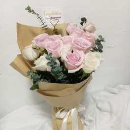 Pink and white rose bouquet wrapped in kraft paper with a ribbon