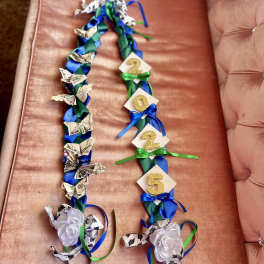 Two ribbon garlands with paper flowers and glitter numbers on a pink couch