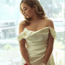 Bride in an ivory off-shoulder gown holding a bouquet of red roses