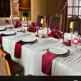 Wedding reception table with red floral centerpieces and gold candle holders