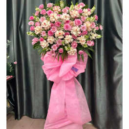 Pink and white floral standing spray with a large pink bow
