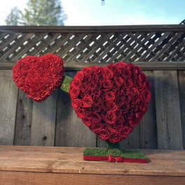 Two red heart-shaped floral arrangements on stands, one made of roses