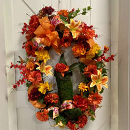 Autumn wreath with orange and red flowers on a white door