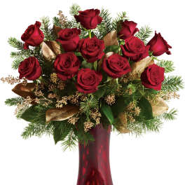 Red roses arranged in a red vase with gold ribbon accents