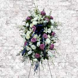 Standing floral wreath with purple and white flowers on an easel