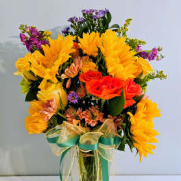 Bright mixed bouquet with sunflowers and roses in a clear glass vase