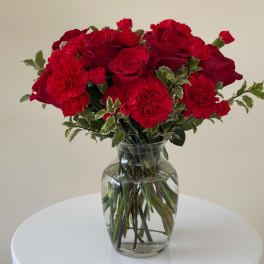 Red roses and carnations in a clear glass vase
