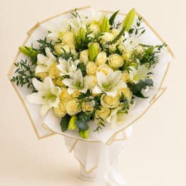 Bouquet of white lilies and pale yellow roses wrapped in white paper