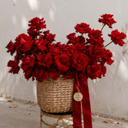 Basket of red roses with a red ribbon on a gold stand