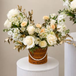 White and peach rose arrangement in a wicker basket with pearl trim