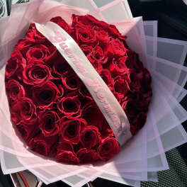 Bouquet of red roses wrapped in pink paper with a satin ribbon