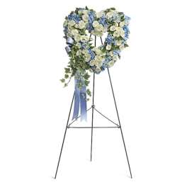 Heart-shaped floral wreath on a standing easel with blue and white flowers