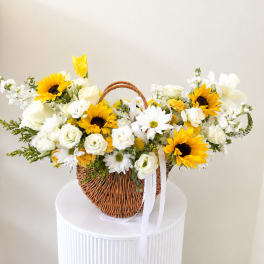 Basket of white and yellow flowers with a white ribbon