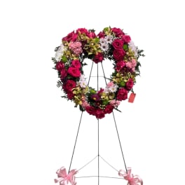 Heart-shaped floral wreath on a standing easel with pink ribbons