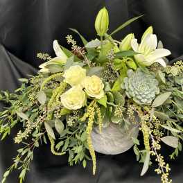 White lilies and pale roses in a low arrangement with a succulent