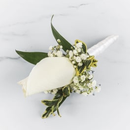 White calla lily boutonniere with small white flowers and green leaves