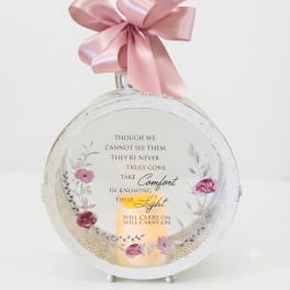Round memorial plaque with a pink ribbon bow and candle design