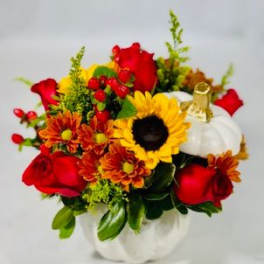 Bouquet of red roses, sunflowers, and orange mums in a white pumpkin container