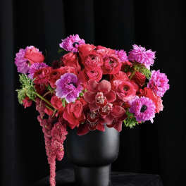Pink and red floral arrangement in a black vase