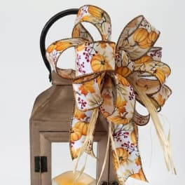 Wooden lantern with a pumpkin-pattern ribbon bow and candle inside