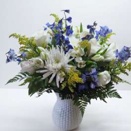 White and blue mixed flower arrangement in a textured white vase