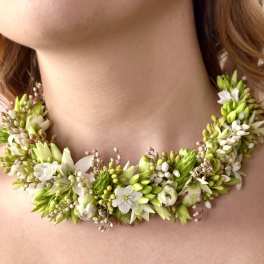 Floral necklace with white and green blossoms around a woman's neck