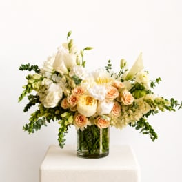 Cream and peach floral arrangement in a clear glass vase