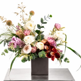 Mixed floral arrangement in a dark square vase with pink, white, and burgundy blooms