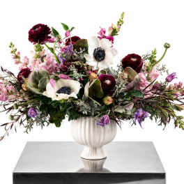 Large mixed floral arrangement in a white pedestal vase