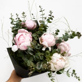 Pink and white peonies arranged with eucalyptus in black wrap