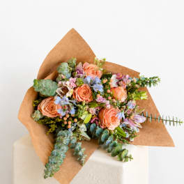 Peach roses and pastel flowers wrapped in brown paper