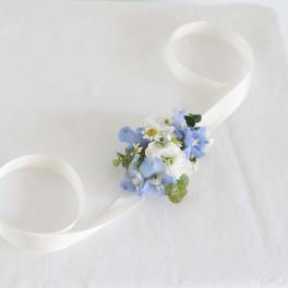 White ribbon wrist corsage with blue and white flowers