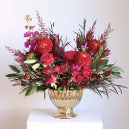 Pink and red floral arrangement in a gold vase