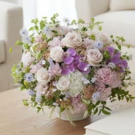 Pastel bouquet of roses, orchids, and hydrangeas in a white vase