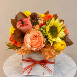 Autumn floral arrangement with roses and a sunflower in a square box