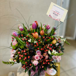 Mixed bouquet with pink roses, tulips, and berries in a gift box