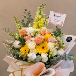 Bouquet of peach and white roses with yellow flowers in a glass vase