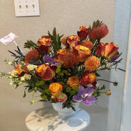 Bright mixed bouquet in a white vase with orange, red, and purple blooms