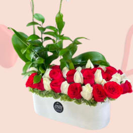 White orchids rise above red and white roses in a white box arrangement.