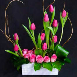 Pink tulips and roses arranged in a white rectangular container