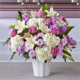 Pink roses and white lilies arranged in a white vase