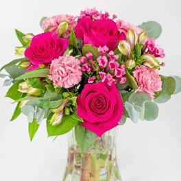 Pink roses and carnations arranged in a clear glass vase