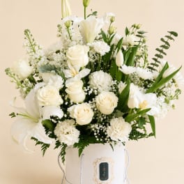 White floral arrangement in a white hatbox with lilies and roses