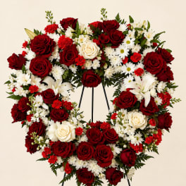 Heart-shaped wreath of red and white flowers on a stand