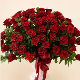 Large bouquet of red roses in a white vase with a red ribbon