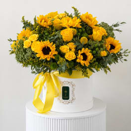 Yellow sunflowers and roses arranged in a white hat box with a yellow ribbon
